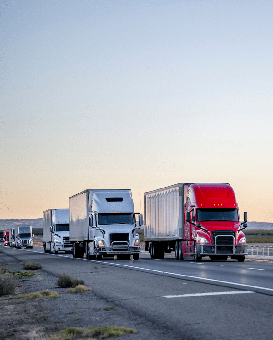 Trucks driving on a highway at dusk.